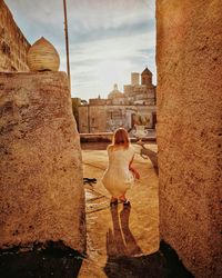 Rear view of woman looking at buildings against sky