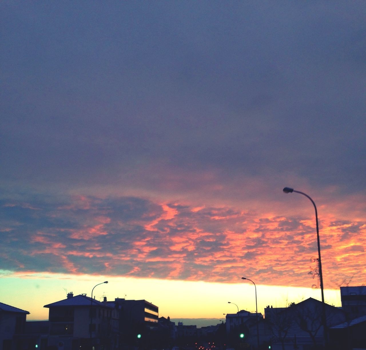 sunset, building exterior, architecture, sky, built structure, cloud - sky, silhouette, low angle view, orange color, street light, city, cloudy, residential structure, cloud, house, dusk, residential building, building, dramatic sky, outdoors