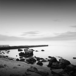 Pier at beach against sky during foggy weather