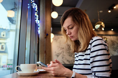 Woman have breakfast at cafe, use smartphone at cafe
