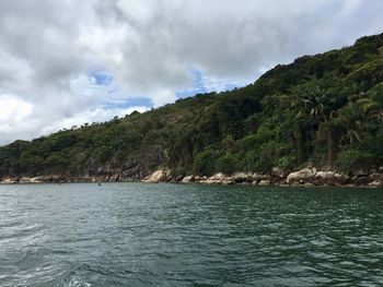 Scenic view of lake by mountain against cloudy sky