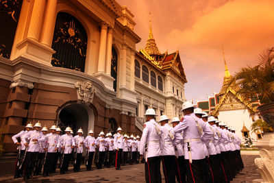 Army soldiers standing by historic building during sunset