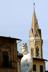 Low angle view of statue against building against sky