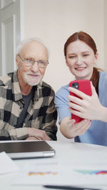 Portrait of smiling woman taking selfie with senior man