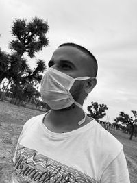 Close-up of man wearing mask standing against sky