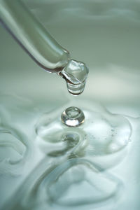 Dropper with serum or cosmetic oil on a green background.