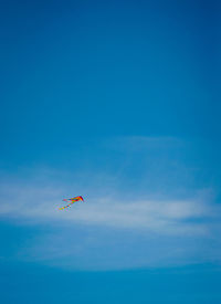 Low angle view of people paragliding against blue sky