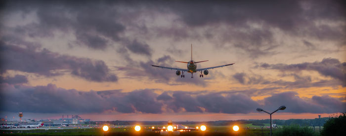 Low angle view of airplane flying against sky during sunset