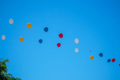 Low angle view of balloons against clear blue sky