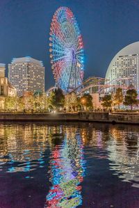 Illuminated ferris wheel in city at night