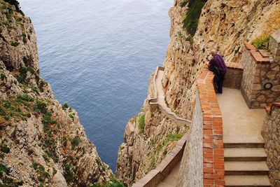 High angle view of man using smart phone while standing by railing at mountain