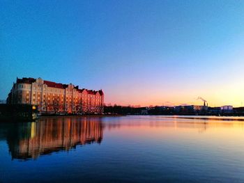 Scenic view of lake by buildings against clear sky at dusk