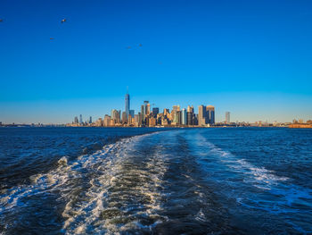 Scenic view of sea by buildings against blue sky