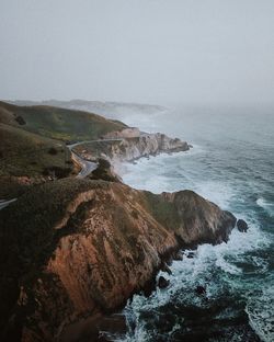 Scenic view of sea by mountains against clear sky