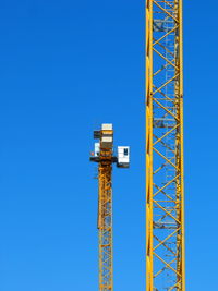 Low angle view of crane against clear blue sky