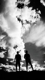 Low angle view of silhouette men standing against sky