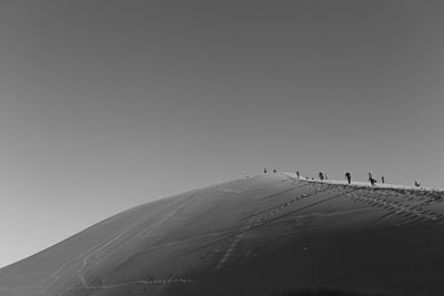 People on mountain against clear sky