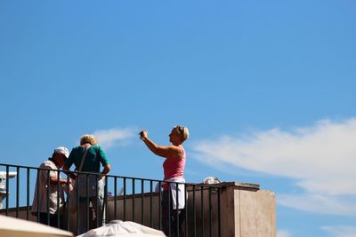 Low angle view of friends standing against railing