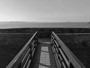 Boardwalk leading towards sea against sky