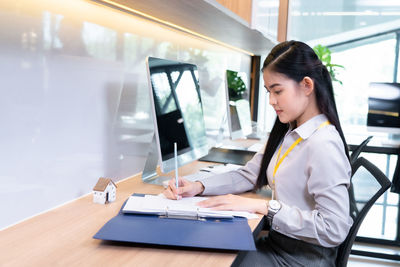 Young woman using laptop while sitting in office