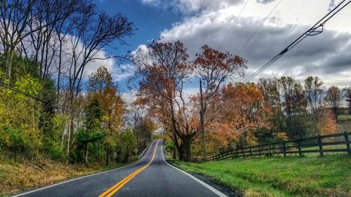 Road amidst trees against sky during autumn