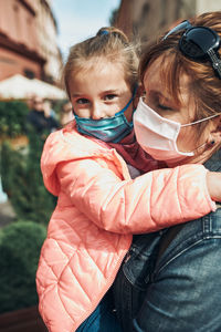 Close-up of mother and daughter wearing mask standing outdoors