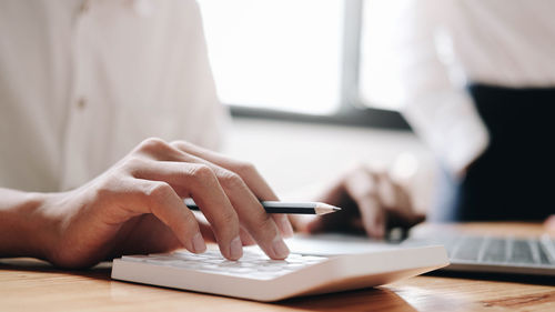 Midsection of man using smart phone on table