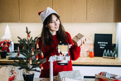 Portrait of young woman using mobile phone while sitting on table