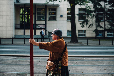 Rear view of man standing on street against building in city