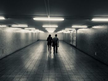 Rear view of people walking in illuminated tunnel