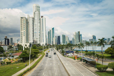 City street by modern buildings against sky