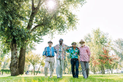 Rear view of people standing against trees