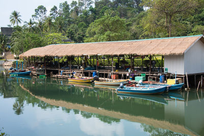 Boats moored by lake against trees and building