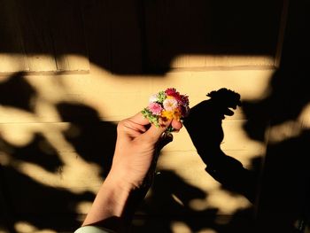 Cropped image of people holding flower against blurred background