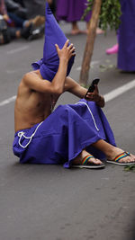 Cucurucho priest shirtless talking on a cell phone during the procession of jesus of the great power