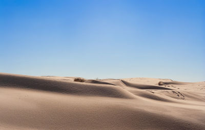 Scenic view of desert against clear blue sky