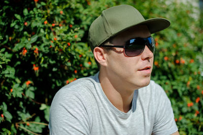 Close-up of mid adult man wearing sunglasses standing by plants at park
