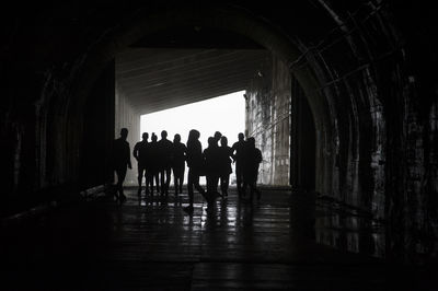 Silhouette people walking in tunnel