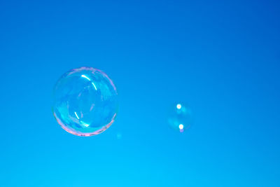 Low angle view of bubbles against blue background