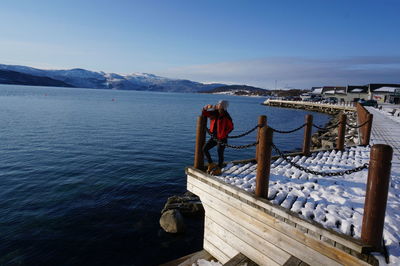 Man standing on pier by sea against sky