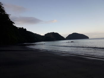 Scenic view of beach against sky at sunset