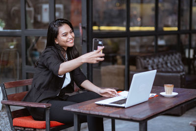 Businesswoman using laptop while sitting at cafe