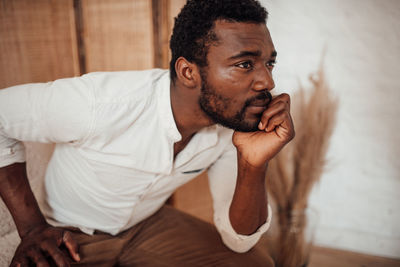 Young man looking away while sitting at home