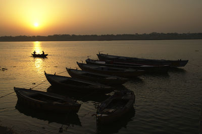 Boat moored in lake against sky during sunset