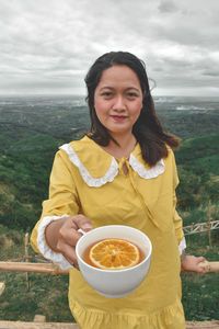 Portrait of a smiling woman with orange tea on cup