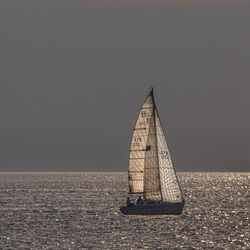 A lone sailboat crosses the sparkling waters