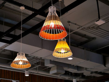 Low angle view of illuminated pendant lights hanging on ceiling