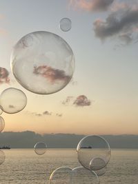 Bubbles over sea against sky during sunset
