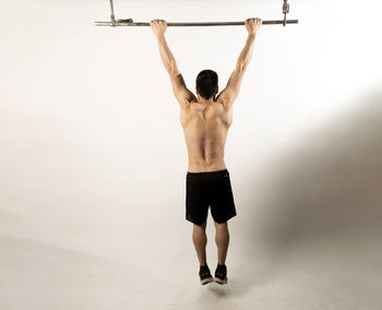 Rear view of shirtless man standing against wall