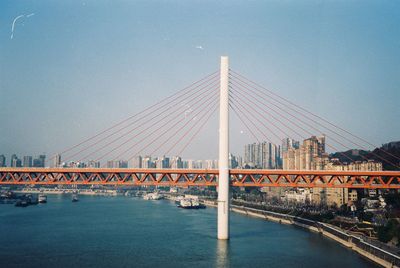 Suspension bridge over river against clear blue sky